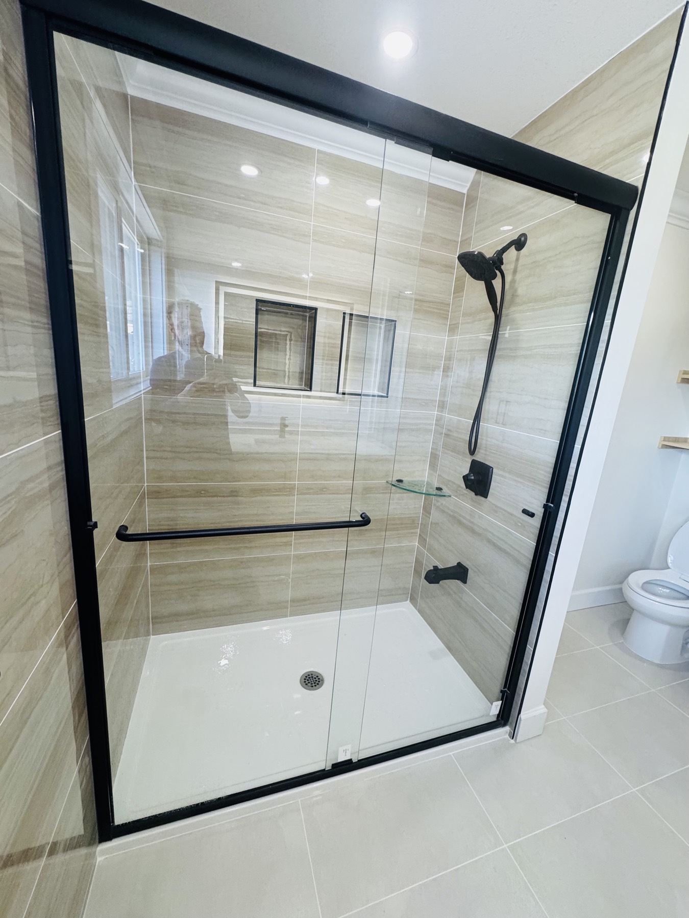 Walk in shower with black framed glass and full height wall tile