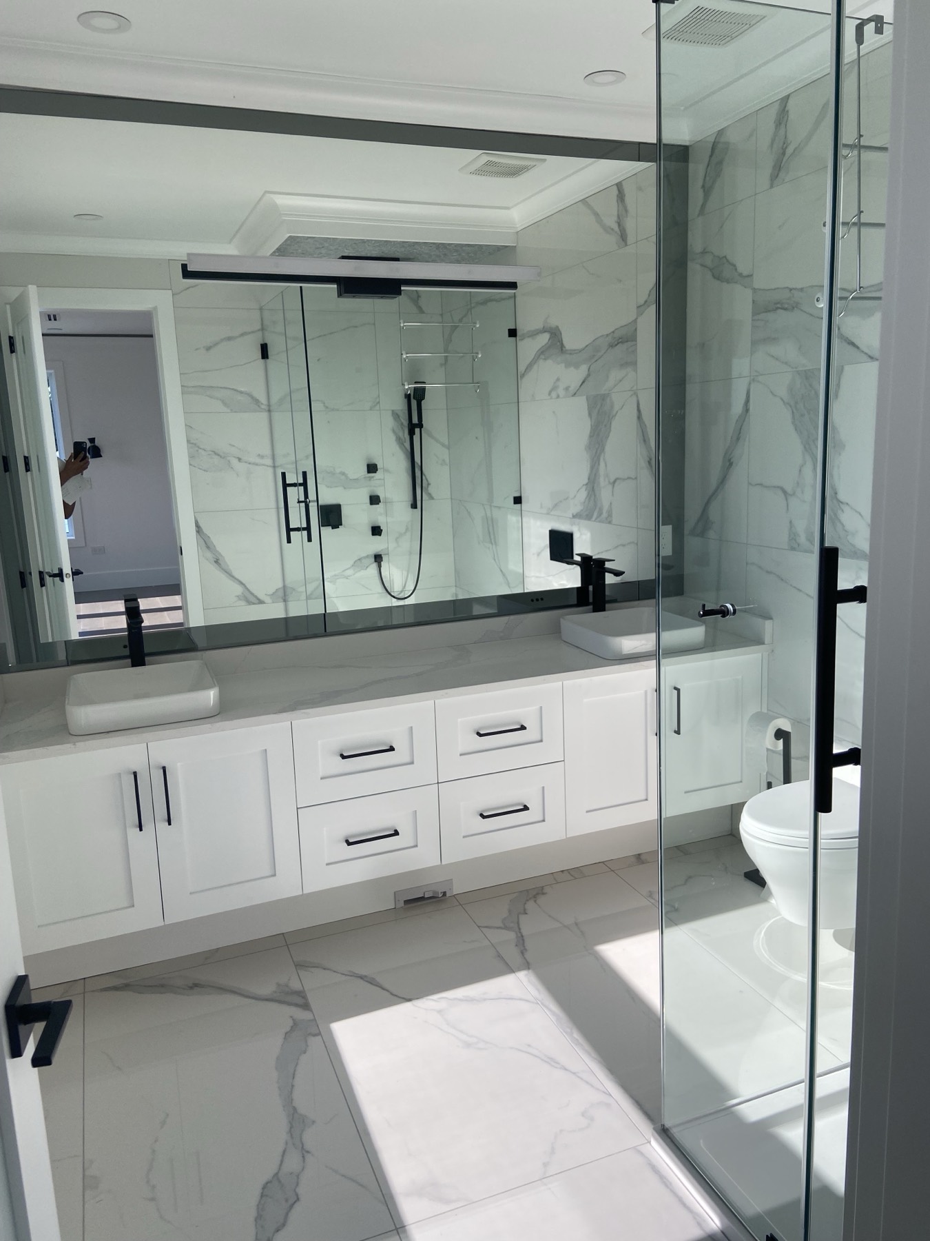 Renovated washroom with glass shower, large format wall tile and black fixtures