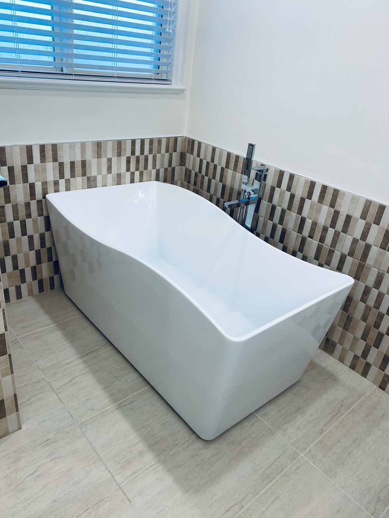Freestanding bath against a mosaic tile feature wall