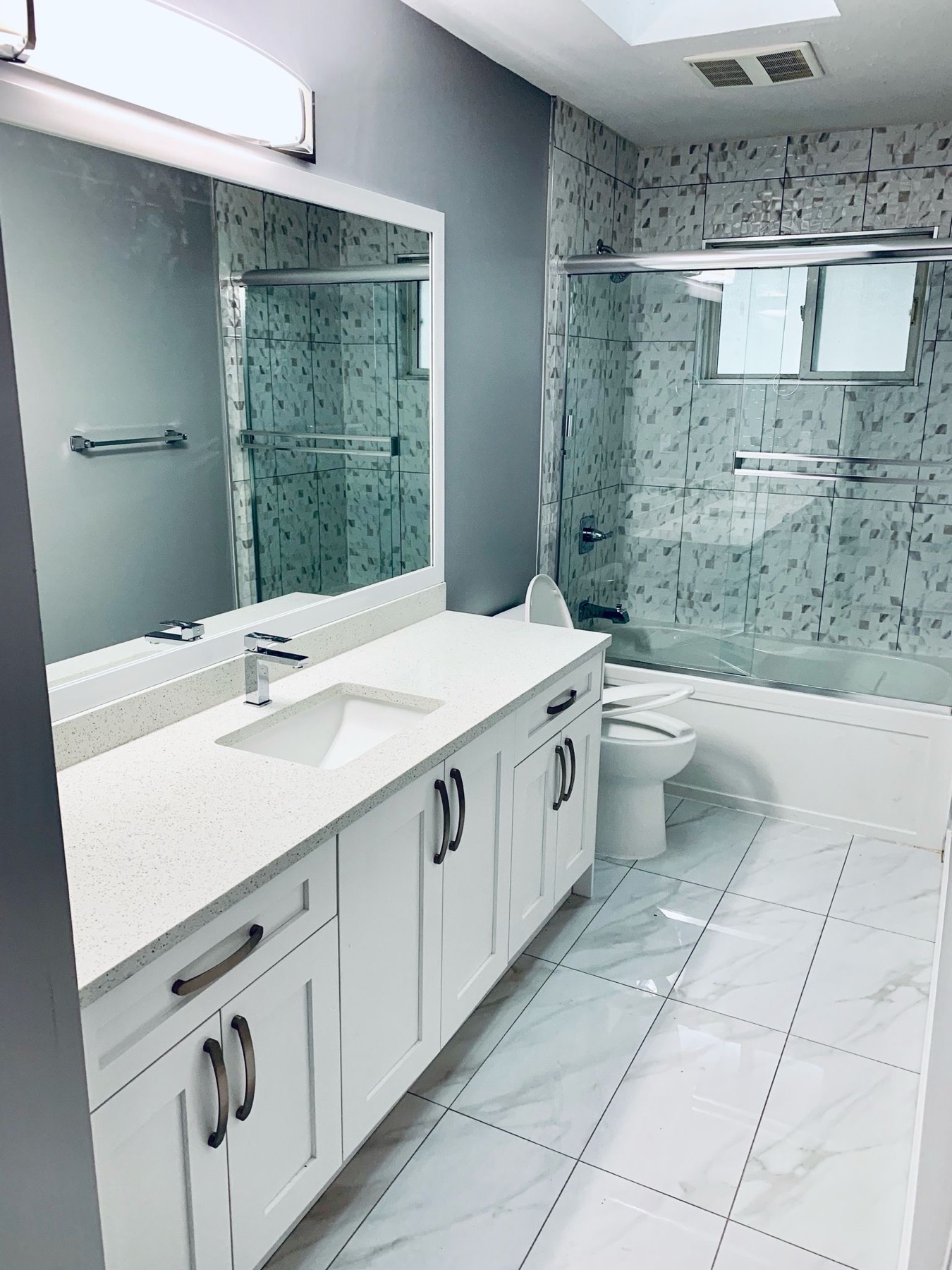 Washroom with mosaic shower wall and stone counter